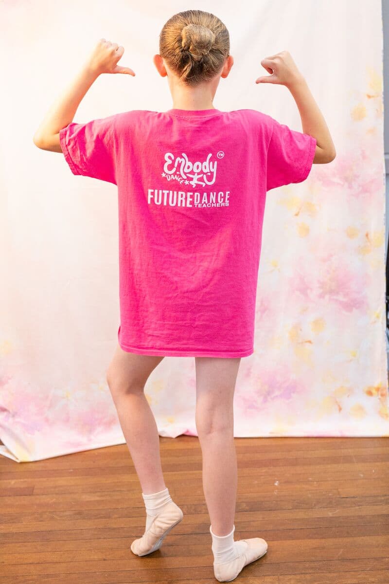 Future Dance Teacher pointing to the Future Dance Teachers logo on the back of a t-shirt